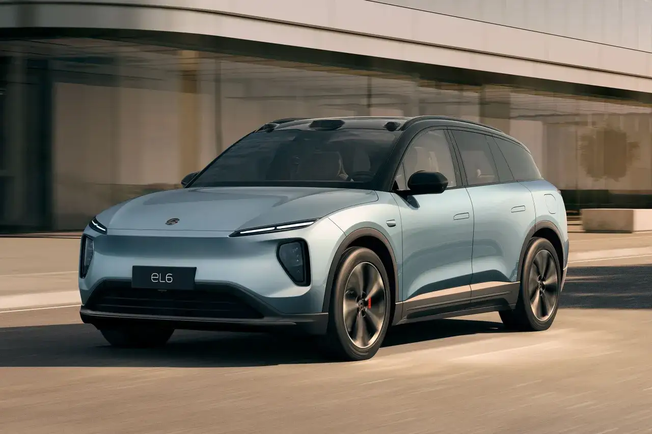 La nio auto EL6 blu metallizzato sfreccia su una strada moderna, con un design elegante e futuristico.