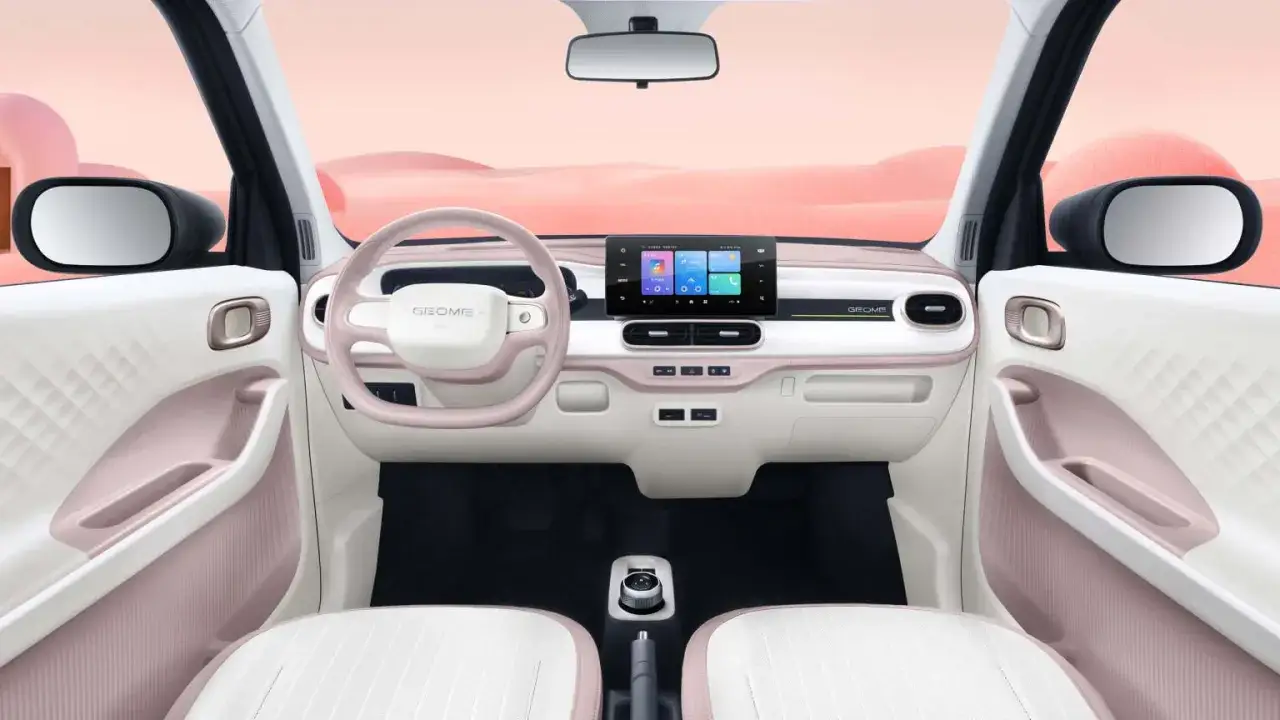 Interni del Geely Panda: volante rosa, cruscotto bianco e rosa con touchscreen, sedili bianchi.