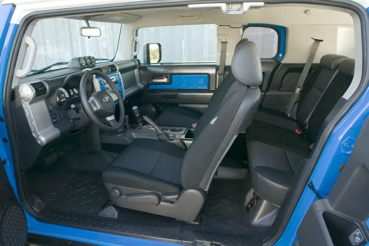 Interno blu e nero di un Toyota Land Cruiser mini, con sedili in tessuto e cruscotto funzionale.