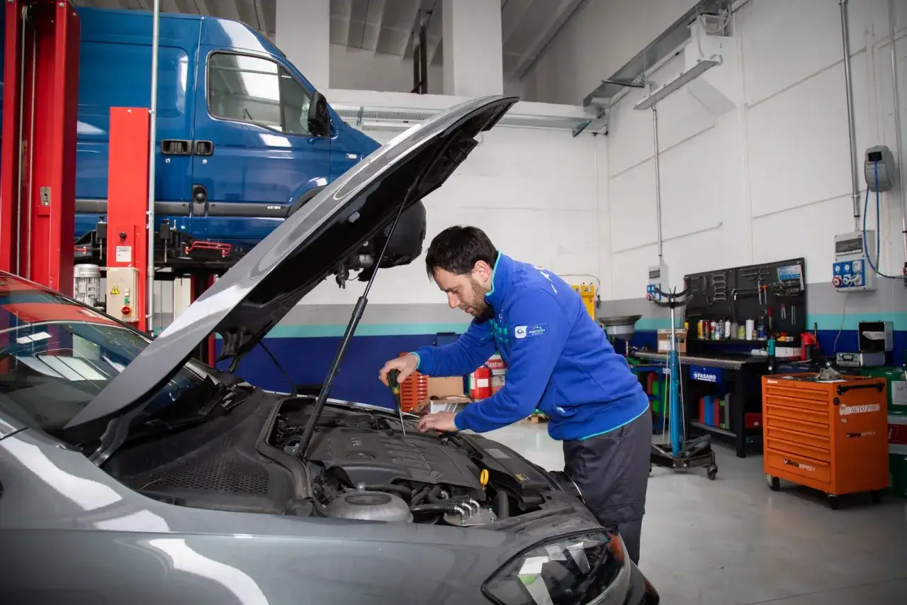 Meccanico effettua il lavaggio cambio automatico su un'auto in officina.