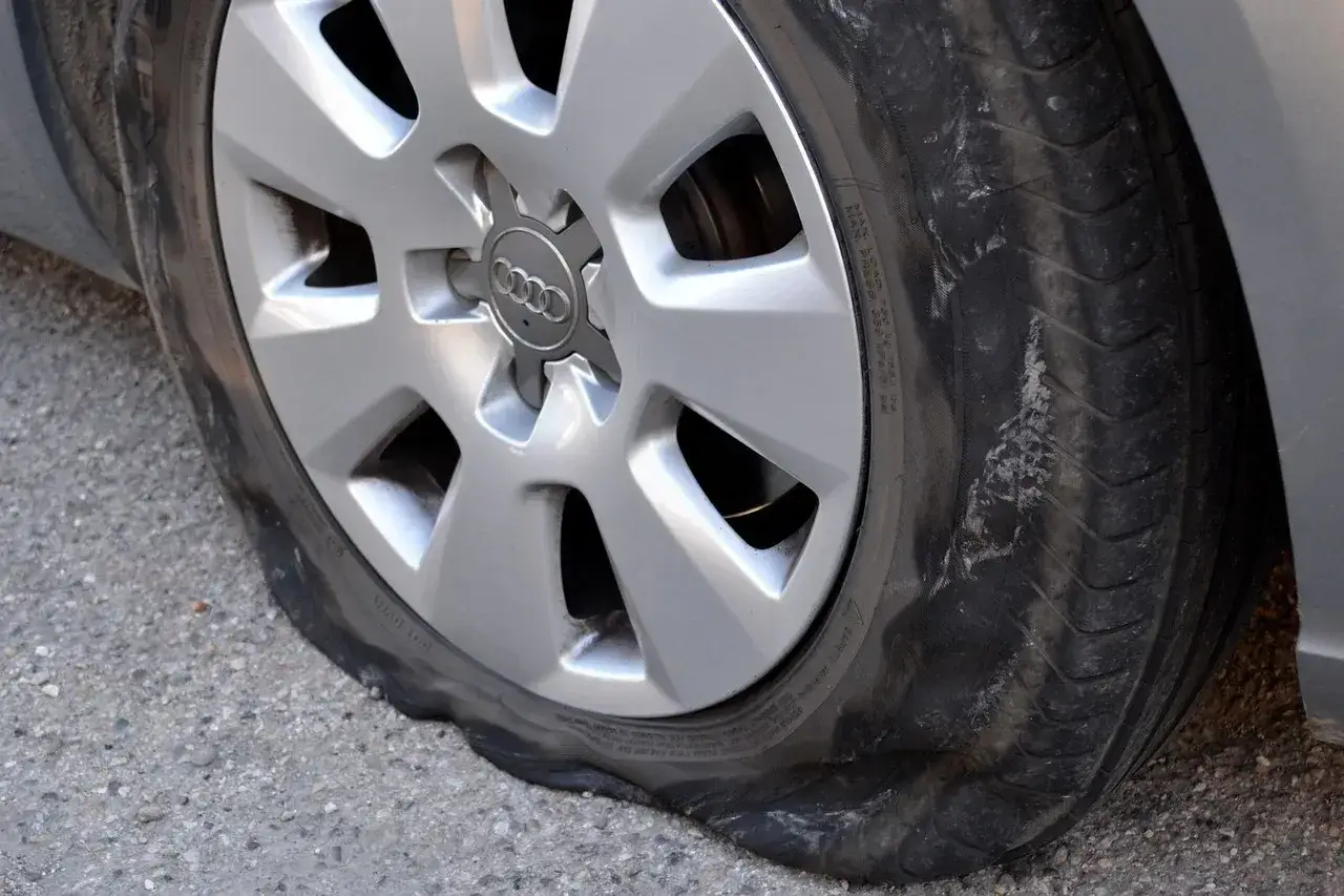 Gomma bucata su un cerchio Audi, il pneumatico è completamente sgonfio e deformato sull'asfalto.