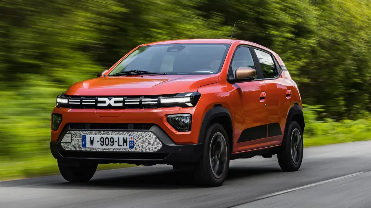 Dacia Spring arancione sfreccia in autostrada, dimostrando la sua autonomia per viaggi lunghi.