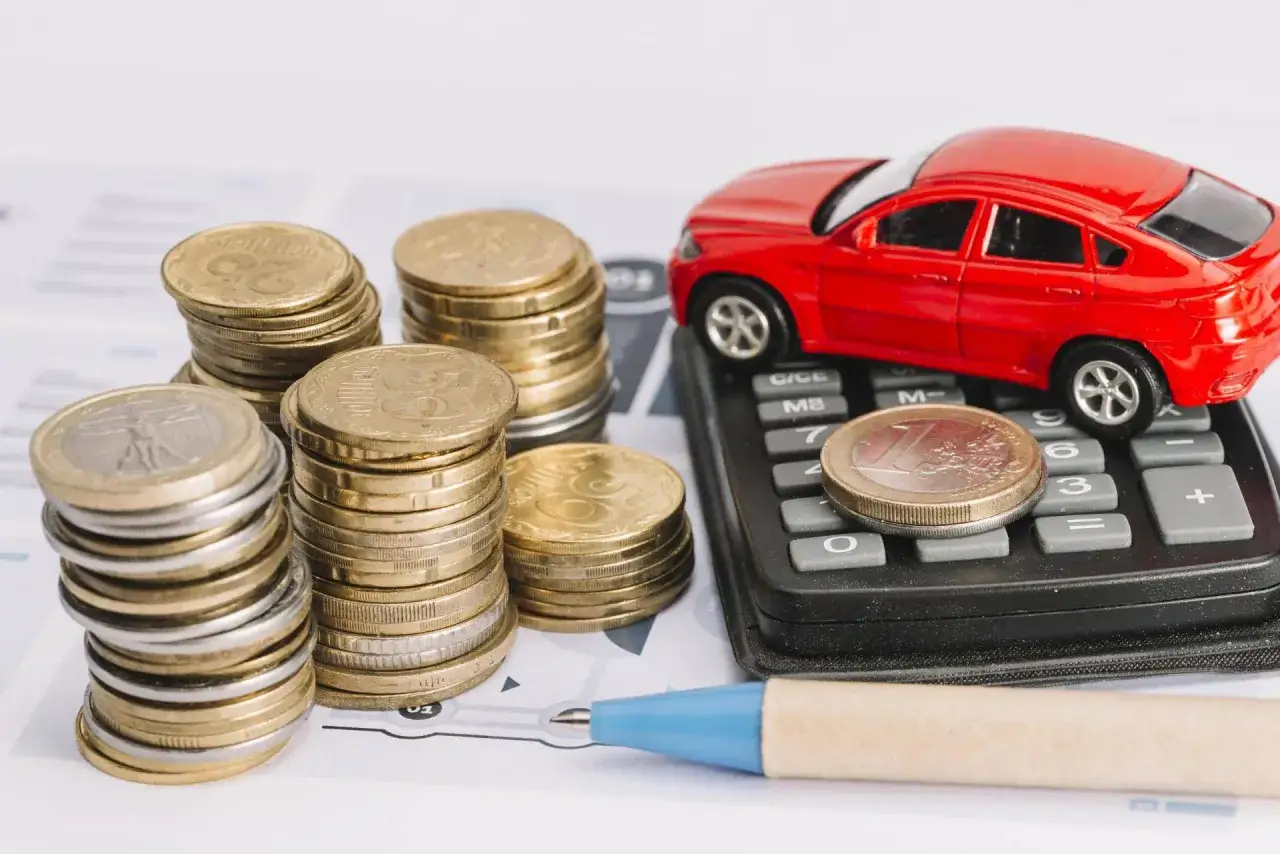 Monete e macchinina rossa su calcolatrice, per calcolare il bollo auto elettriche in Veneto.