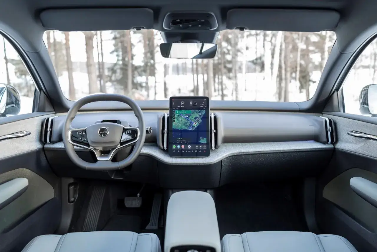 Interni minimalisti della Volvo EX30: volante, grande schermo centrale con navigazione e finiture moderne.