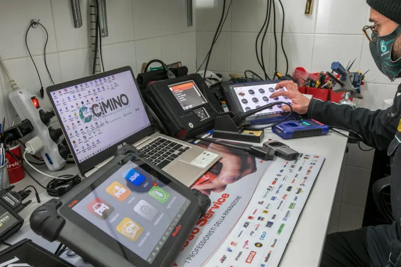 Tecnico effettua aggiornamento centralina auto con strumenti diagnostici avanzati.