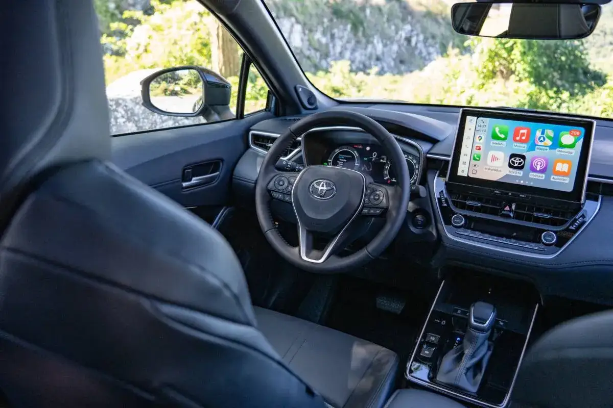 Interno della Toyota Corolla 2026 con ampio display touchscreen e volante multifunzione.