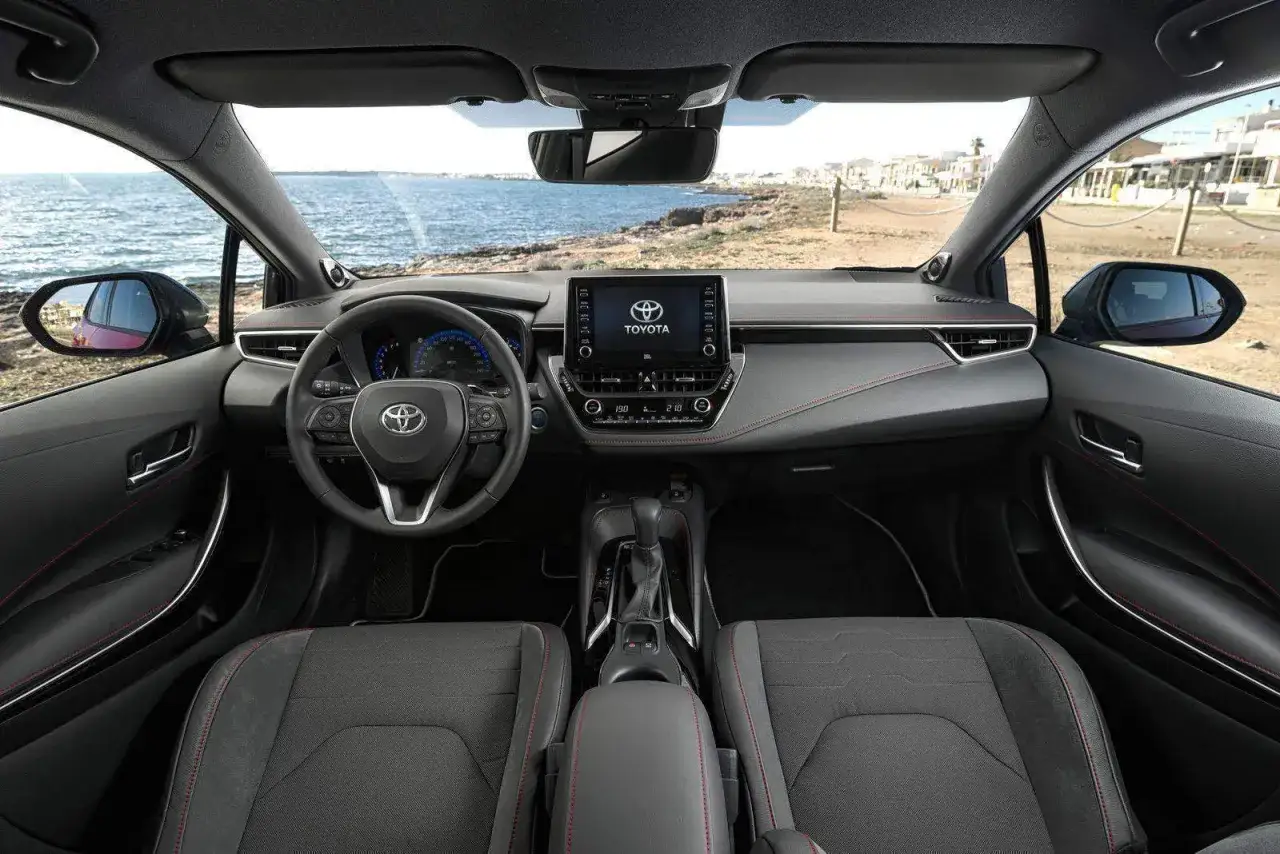 Interno della Toyota Corolla, con volante, cruscotto e sedili sportivi. Le diverse motorizzazioni offrono un'esperienza di guida dinamica.