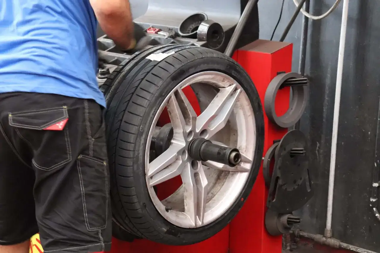 Un meccanico lavora su una ruota montata su una macchina equilibratrice. Quanto tempo ci vuole per cambiare 4 gomme? Dipende dall'efficienza del meccanico e dall'attrezzatura.