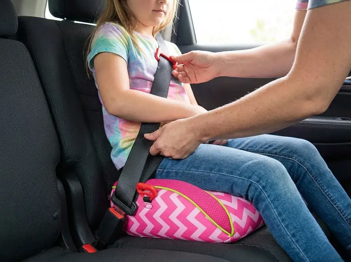 Bambina su alzatina auto con cintura allacciata. Seguire le alzatina auto regole per la sicurezza.