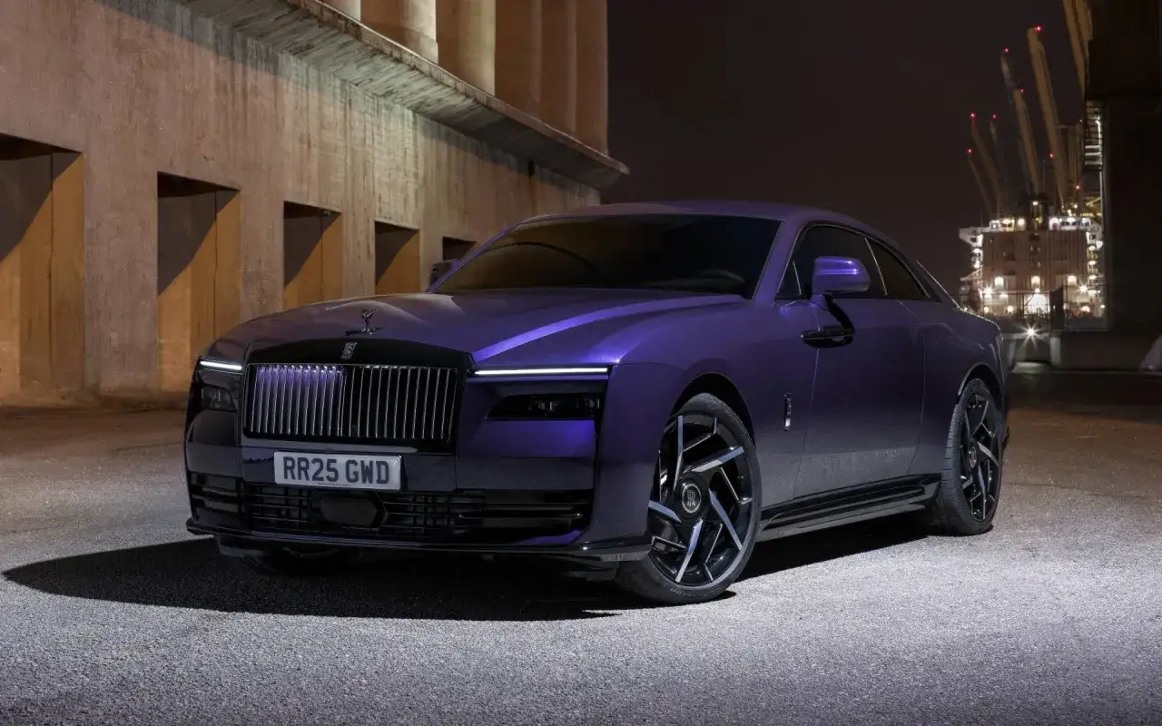 Rolls-Royce Wraith sportiva viola metallizzato, con cerchi neri e sfondo industriale notturno.