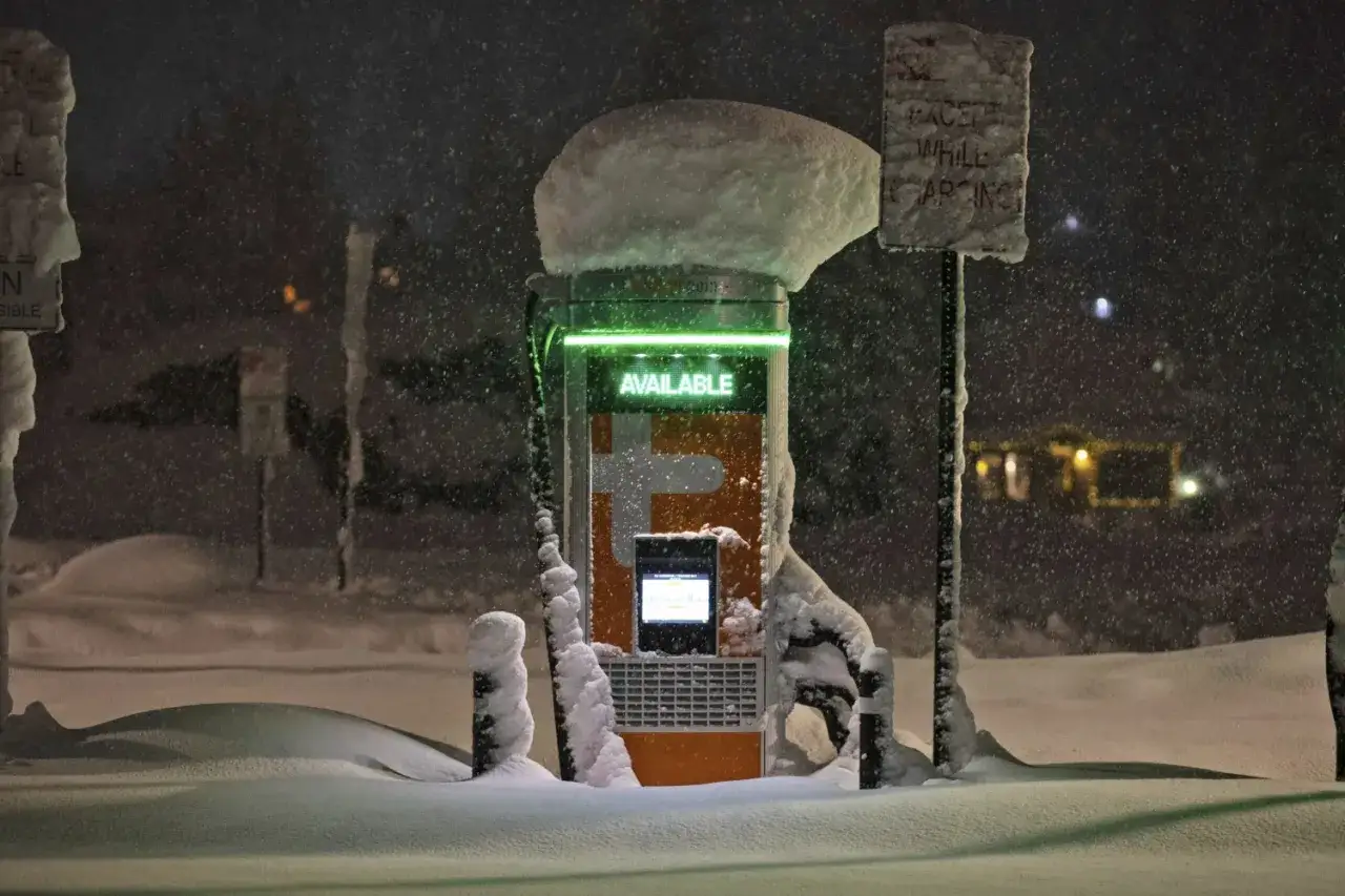Stazione di ricarica per auto elettriche coperta di neve, con la scritta 