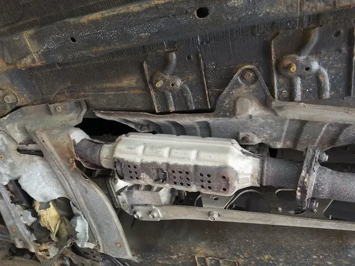 Sottoscocca auto con catalizzatore auto arrugginito e danneggiato, parte di un sistema di scarico da riparare.