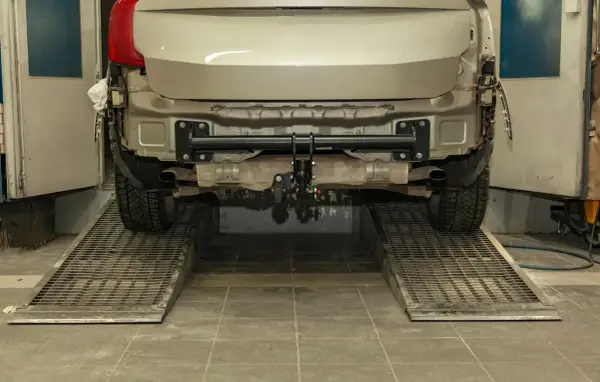 Installazione gancio traino auto: il costo varia in base al modello. L'auto è sollevata su rampe in officina.