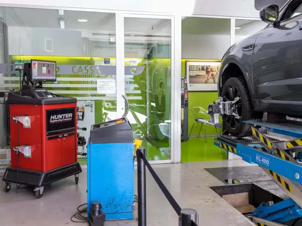 Attrezzatura per la convergenza auto in officina. Un'auto è sollevata su un ponte, con sensori applicati alla ruota.