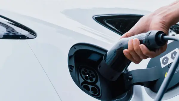 Mano inserisce la spina per trasformare l'auto in elettrica. Ricarica di un veicolo a zero emissioni.