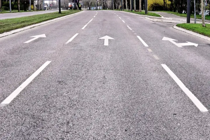Strada con frecce bianche che indicano le corsie di canalizzazione.
